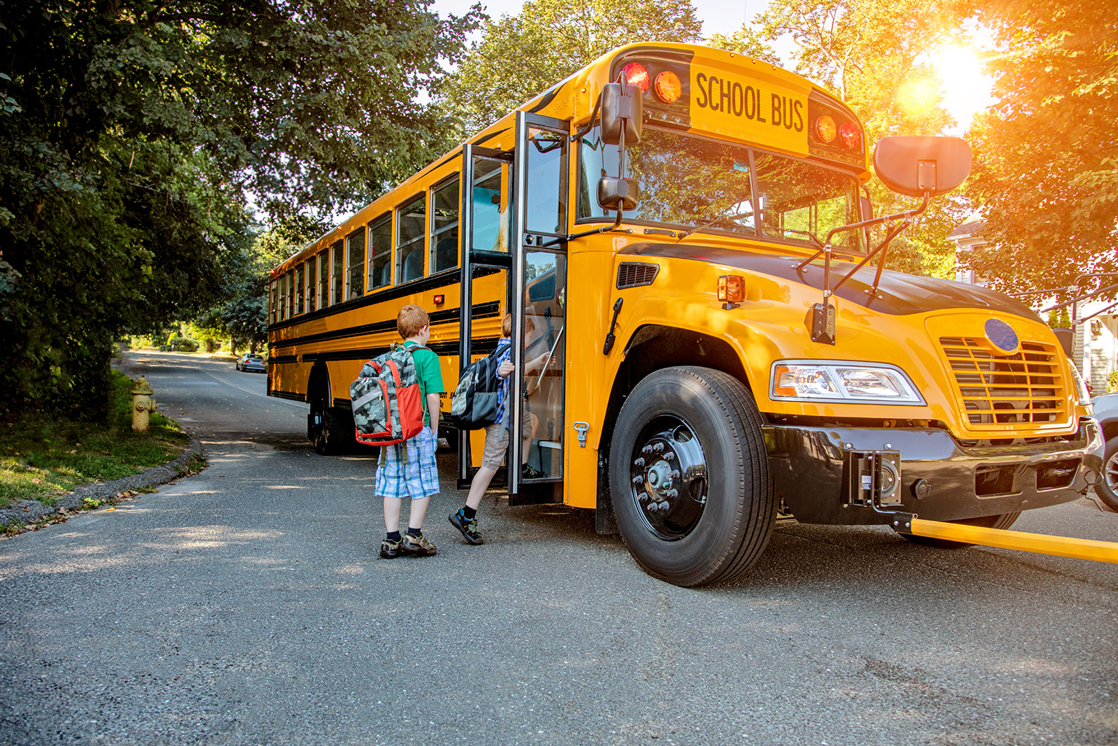A yellow school bus picking up young students.